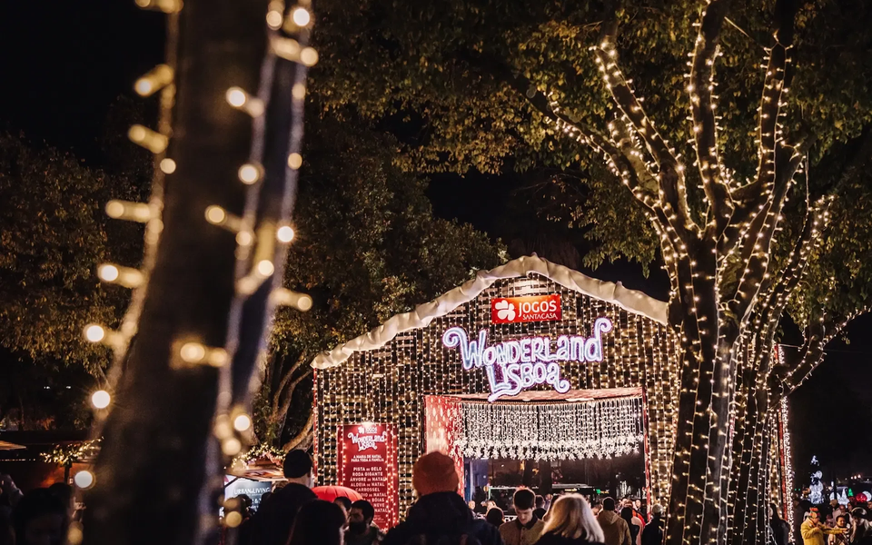 Crowd entering Wonderland Lisboa at night through illuminated entrance with Christmas lights and Jogos Santa Casa sign